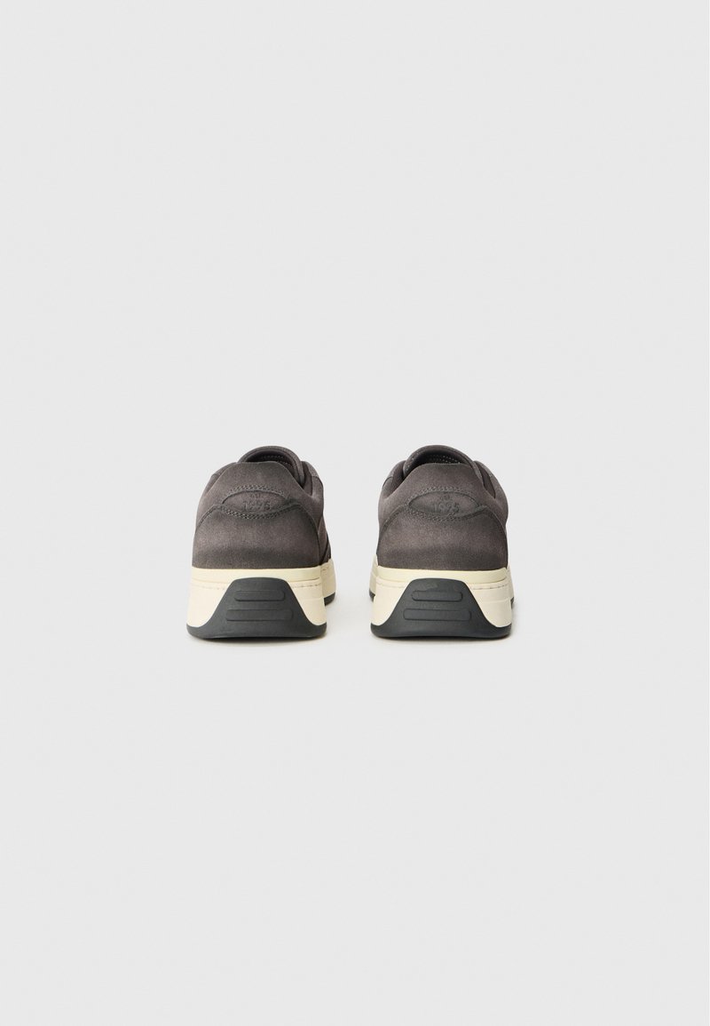 Grijze suède sneakers met een crèmekleurige tussenzool en zwarte rubberen buitenzool, met ronde achterkant en subtiele stiksels.