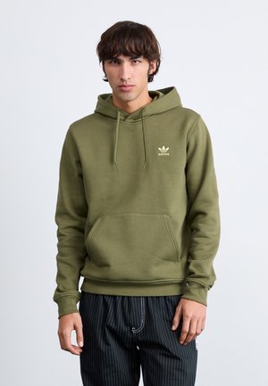 Olivgrüner Kapuzenpullover mit einer Vordertasche, langen Ärmeln und einem kleinen beigen Adidas-Logo auf der Brust. Weiche Stofftextur.