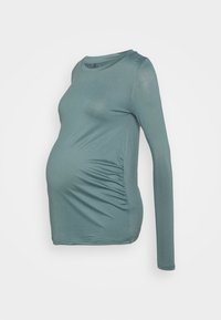 Blusa de maternidade de manga longa em verde azulado suave, com um leve brilho, franzido de lado e decote redondo. Tecido macio e elástico.
