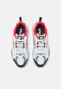 Białe sportowe sneakersy z czerwonymi i granatowymi akcentami, z siateczki i materiałów syntetycznych, z wyściółką przy kołnierzu i płaskimi sznurowadłami. Logo na języku i boku.