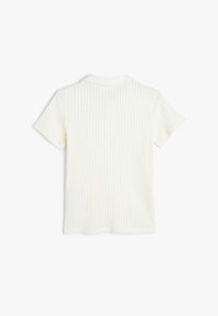 Polo de manga corta y canalé en un color blanco roto con un cuello clásico y un diseño ajustado. Textura suave con sutiles rayas verticales.