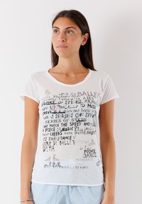 Bílý krátký rukáv tričko s kulatým v�ýstřihem, zdobené černým textem a ilustracemi baletu. Měkká bavlněná tkanina s volným střihem.