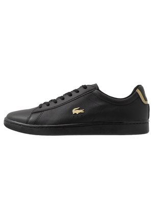 Czarny niskoprofilowy sneaker z perforowaną skórzaną cholewką, czarnymi sznurówkami, czarną podeszwą i złotym logo na boku i na języku z tyłu.
