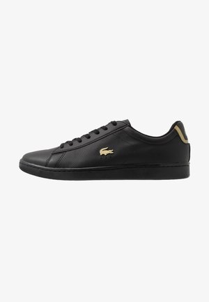 Sneaker nero basso con tomaia in pelle forata, lacci neri, suola nera e logo dorato sul lato e sul tallone.