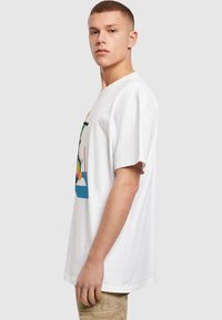 Hvid bomulds T-shirt med et farverigt grafisk design. Korte ærmer, afslappet pasform, rund halsudskæring, glat tekstur.