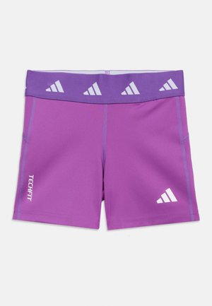 Lilla Adidas Techfit kompresjonsshorts med elastisk linning som har hvite Adidas-logoer på linningen og benet.
