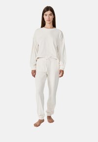 Ensemble de vêtements d'intérieur de couleur crème comprenant un haut ample à manches longues et un pantalon fuselé avec une taille élastique et un cordon de serrage.