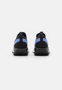 Zwarte sportieve schoenen met blauwe accenten, bovenwerk van mesh en een chunky witte zool. Bevat een treklipje aan de achterkant en een gestructureerd profiel op de zool.