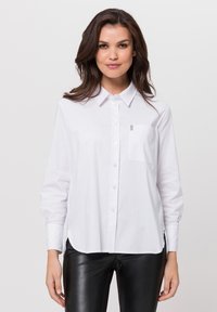 Weißes Button-down-Hemd mit langen Ärmeln, einem Kragen und einer Brusttasche. Weicher Stoff mit geradem Saum und leichten seitlichen Schlitzen für mehr Bewegungsfreiheit.