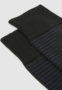 Sorte og marineblå stribede sokker med et struktureret strikmønster, der har en ensfarvet sort manchet. Blødt materiale, der sikrer fleksibilitet og komfort.