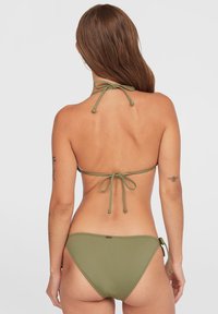 Zestaw bikini w kolorze oliwkowym, wykonany z gładkiego materiału. Górna część w stylu halter z regulowanymi trokami na szyi i plecach; dolna część z akcentami na bocznych trokach.
