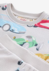 Pull en polaire pour enfants avec col et poignets côtelés, avec des illustrations colorées de voitures sur un fond clair.