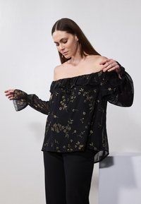 Blusa nera scollata con scollo arruffato e maniche lunghe trasparenti, caratterizzata da motivi floreali dorati e una silhouette fluida.