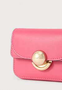 Rózsaszín bőrtok lekerekített fedéllel, arany kör alakú díszítéssel és varrási részletekkel. Kompakt kialakítás sima textúrával és polírozott felülettel.