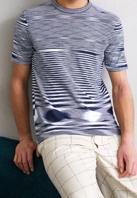 Randig t-shirt i blå och vita nyanser, med rund hals och korta ärmar, med en mjuk struktur och subtila färgvariationer.