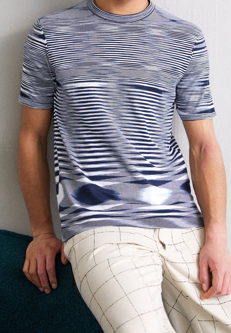 Randig t-shirt i blå och vita nyanser, med rund hals och korta ärmar, med en mjuk struktur och subtila färgvariationer.