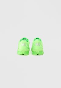 Neongrüne Laufschuhe mit texturiertem, wellenförmigem Design. Sie verfügen über das weiße "GEL"-Label auf der Rückseite und eine gepolsterte Sohle für Komfort.