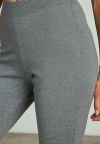 Grijze gebreide leggings met een zachte ribbelband, voorzien van een textuur met subtiele sprankels door de stof.