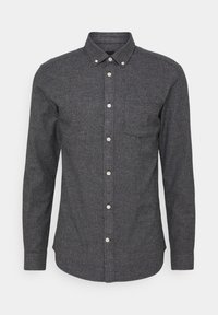 Chemise boutonner grise foncée en tissu texturé, dotée d'un col boutonné et d'une poche poitrine, avec des boutons blancs sur le devant.