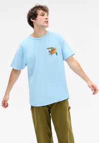 Light blue cotton t-shirt with a round neck, short sleeves, and a front graphic featuring a colorful dragon design.