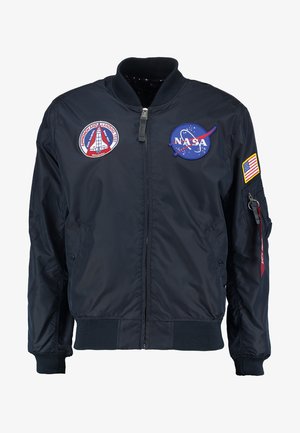 Navy bomber jacket with NASA and mission patches, front zipper, ribbed cuffs, and a small sleeve pocket with a fabric pull tab.