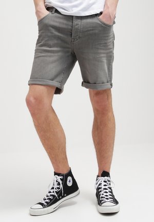 Shorts en jean gris avec revers roulés, dotés de cinq poches, une coupe droite et une finition douce et texturée. Assortis à des baskets montantes noires.
