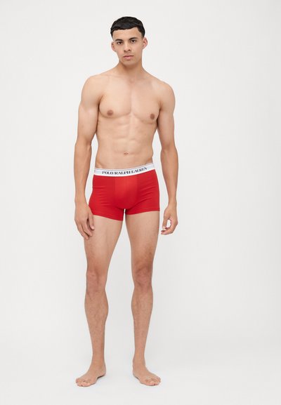 Boxer in cotone elastico rosso con una cintura bianca su cui è scritto "POLO RALPH LAUREN". Design aderente con un taglio a vita media. Stile minimalista.