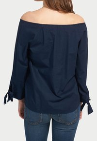 Marineblaue schulterfreie Bluse mit drei Viertelärmeln, ausgestattet mit gebundenen Manschetten und einem glatten, strukturierten Stoff. Lässige Passform.