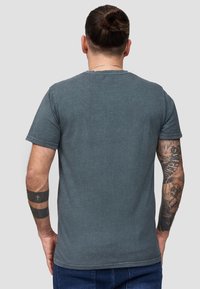 Grijze katoenen t-shirt met korte mouwen, ronde hals en een relaxte pasvorm. Kenmerkt zichtbare stiksels en een gladde textuur. Achteraanzicht.