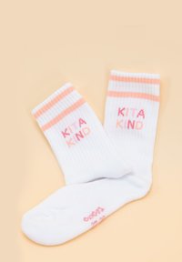 Białe skarpetki w prążki z różowymi paskami na mankiecie. Z nadrukiem "KITA KIND" w różowych literach. Miękki materiał o teksturowanym wyglądzie.