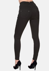 Jeans skinny neri con vita alta, dettaglio testurizzato sul retro e due tasche posteriori, abbinati a scarpe nere con tacco alto.