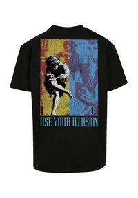 Black t-shirt featuring a graphic print on the back with a figure in motion against yellow and blue backgrounds, and text reading "USE YOUR ILLUSION."