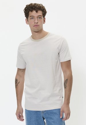 Light gray t-shirt featuring thin horizontal stripes in beige and yellow. Comes with a round neckline and short sleeves. Worn with blue jeans.