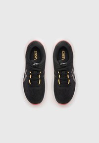 Baskets de sport noires avec une tige en maille, des lacets jaunes et noirs, et une semelle blanche contrastante. Logo Asics en évidence sur les côtés.