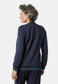 Marineblauwe gestructureerde trui met lange mouwen, een ronde halslijn en contrasterende lichtblauwe strepen bij de manchetten en de onderkant.