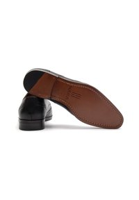 Scarpe eleganti in pelle nera con dettagli brogue, dotate di una suola in pelle marrone e design con punta stretta. Parte superiore testurizzata con dettagli di cucitura.