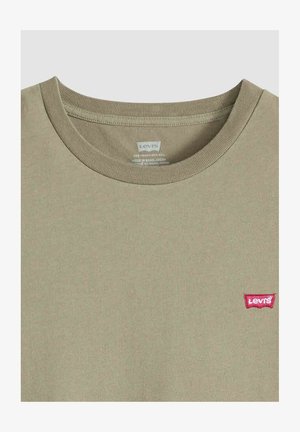 Beiges Levi's T-Shirt mit Rundhalsausschnitt, rotem Logo-Patch auf der linken Brust, sichtbarer Kragennaht und bedrucktem Innenetikett.