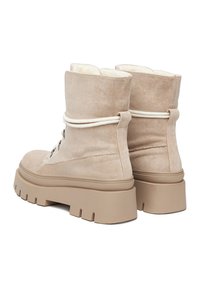 Botine din nubuc bej, cu o platformă din cauciuc masiv, prezentând o căptușeală interioară moale și un detaliu din sfoară albă în jurul gleznei.