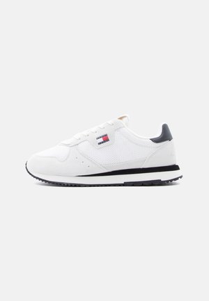 White low-top sneaker with mesh and suede panels, black heel tab, black and white sole, and Tommy Jeans logo on the side.