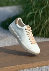 Λευκό δερμάτινο sneaker με υφασμάτινες μπεζ λεπτομέρειες, στρογγυλή μύτη, κορδόνια με παστέλ σχέδιο και μινιμαλιστική σχεδίαση.