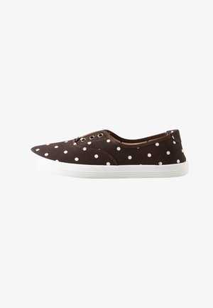 Zapato de lona marrón tipo slip-on con lunares blancos, tres ojales dorados y una suela de goma blanca, mostrado de perfil sobre un fondo blanco.