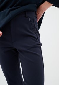 Námořnické modré kalhoty na míru vyrobené z elastické tkaniny, s kapsou na zip, hladkým předním dílem a slim fit střihem. Hladký povrch s elegantním designem.