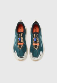 Teal running shoes with a textured upper, orange and blue laces, and white soles. Features GORE-TEX and TERREX branding. Lightweight design.