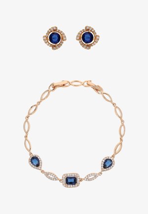 Set de bijuterii cu ton auriu, care include o brățară cu zale ovale alternante și pietre albastre, completată de cercei cu șurub cu un design floral.