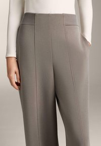 Šedé nohavice s vysokým pásom a hladkým povrchom, vybavené bočnými vreckami a vertikálnymi švovými detailmi, vyrobené z mäkkej elastickej tkaniny.