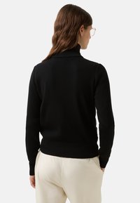 Czarny sweter z długim rękawem i kołnierzem typu stójka, wykonany z miękkiego materiału. Minimalistyczny styl, dopasowana sylwetka i prążkowane detale.