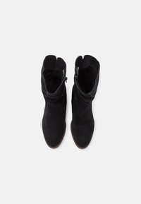 Botines de ante negro con un diseño arrugado, que cuentan con cremalleras a los lados y una textura suave. Suelas marrones.