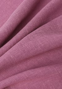 Un tissu texturé et tissé en rose pâle, présentant de doux plis et des variations subtiles dans la densité des fils.