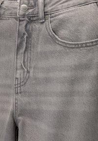 Jeans en denim gris avec une texture légèrement délavée, dotés d'une poche avant, d'une fermeture à bouton et de passants de ceinture. Design classique à cinq poches.