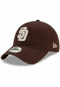 Casquette de baseball marron en tissu, ornée d'un logo "SD" brodé en crème à l'avant et d'un petit logo sur le côté. Ajustement réglable.